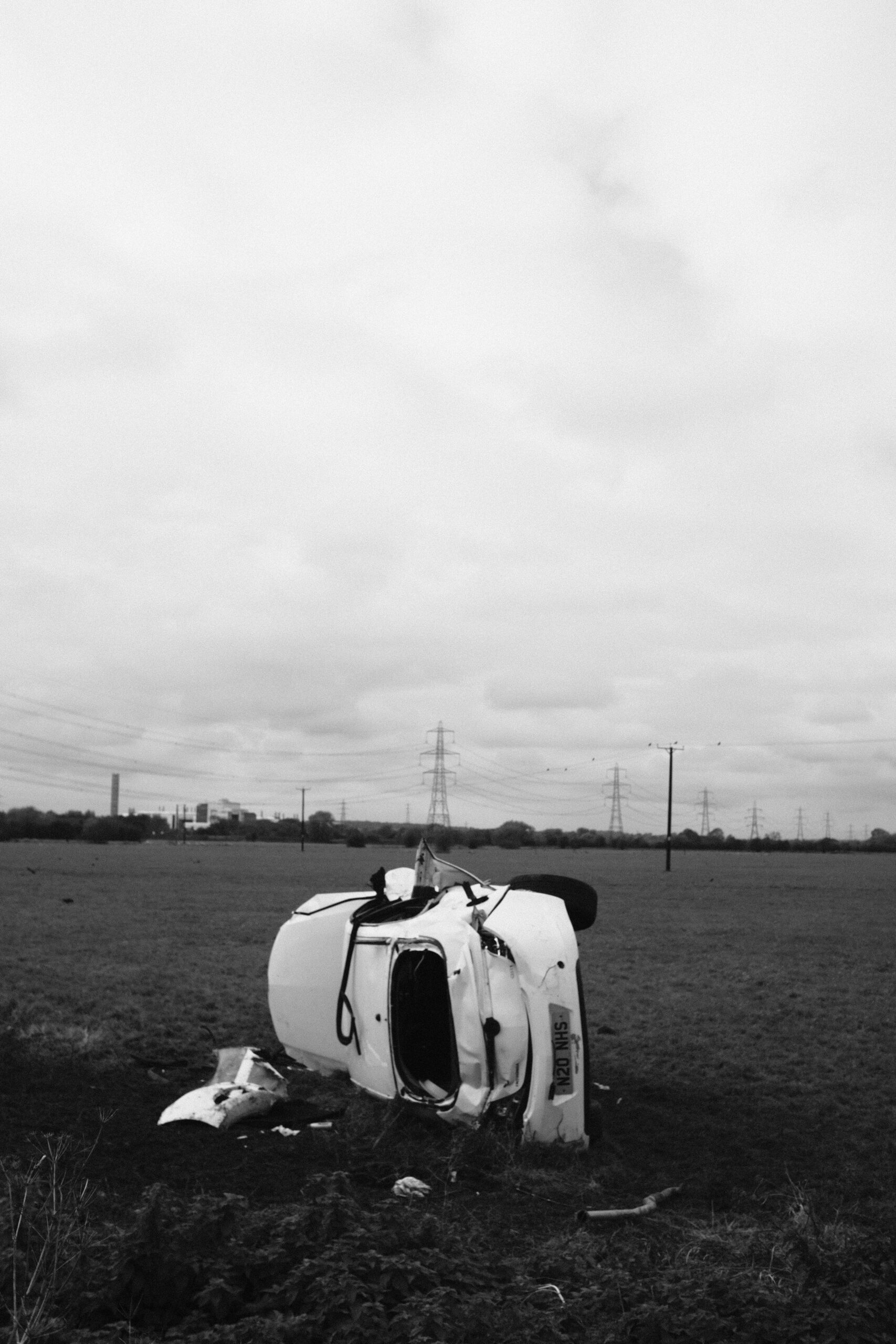 Black and white image of a totaled vehicle in a field after a severe car crash, emphasizing the need for a personal injury lawyer